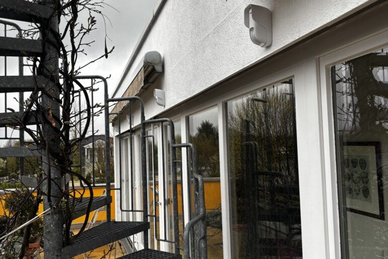 Montierte Kameratechnik an einem Gebäude mit großer Glasfront