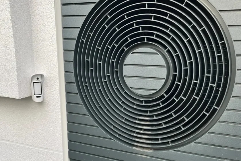 Aussenbewegungsmelder mit Kamera an der Hauswand neben Technik im Garten