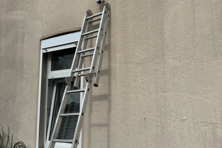 Leiter an einer Fassade bei der Montage einer Außenkamera