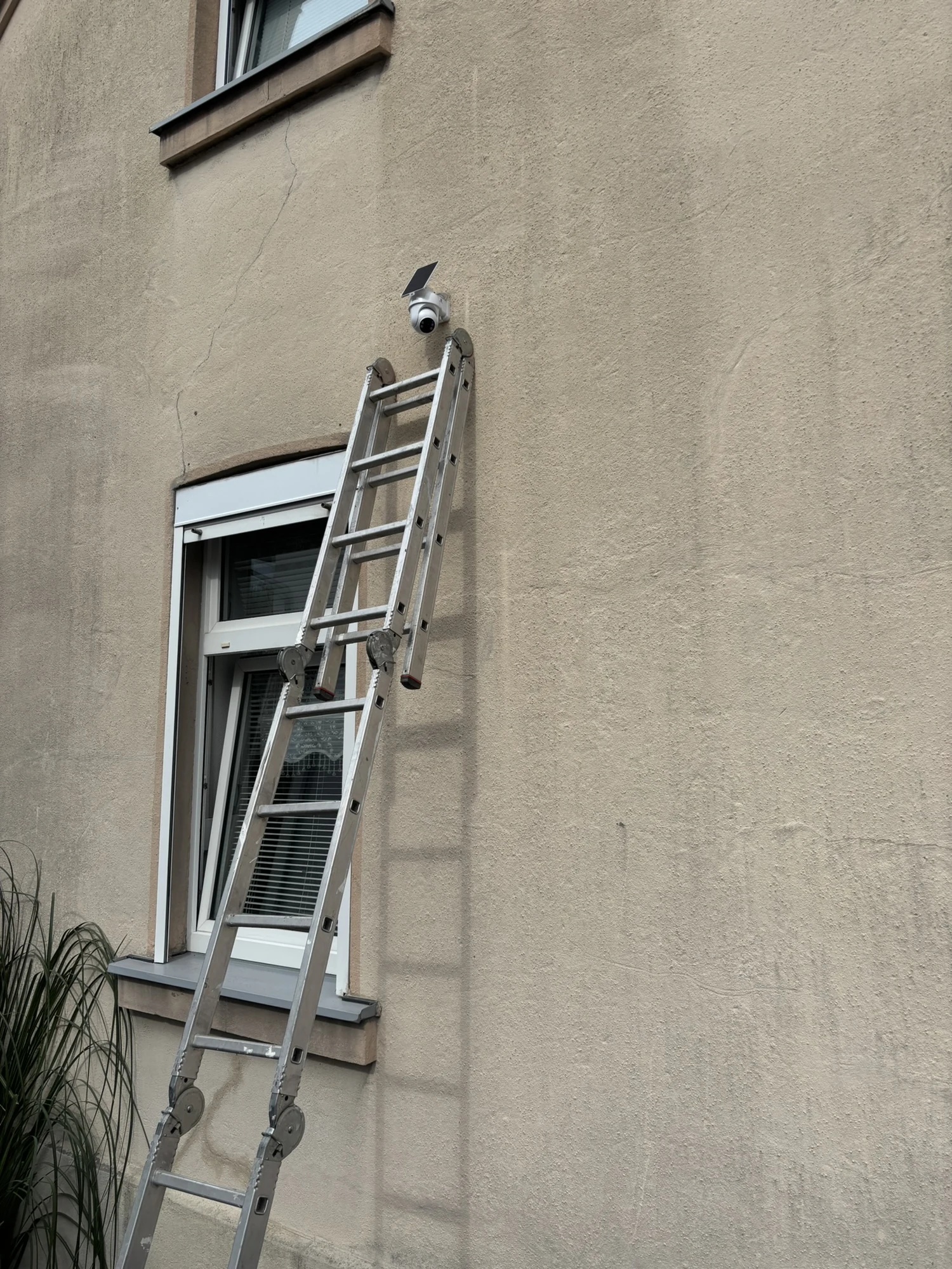 Leiter an einer Fassade bei der Montage einer Außenkamera