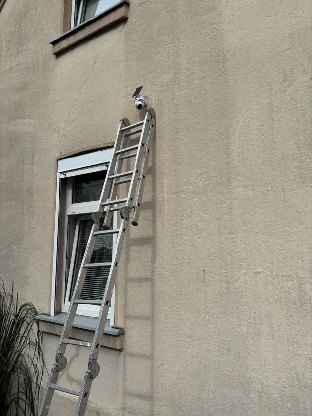 Leiter an einer Fassade bei der Montage einer Außenkamera